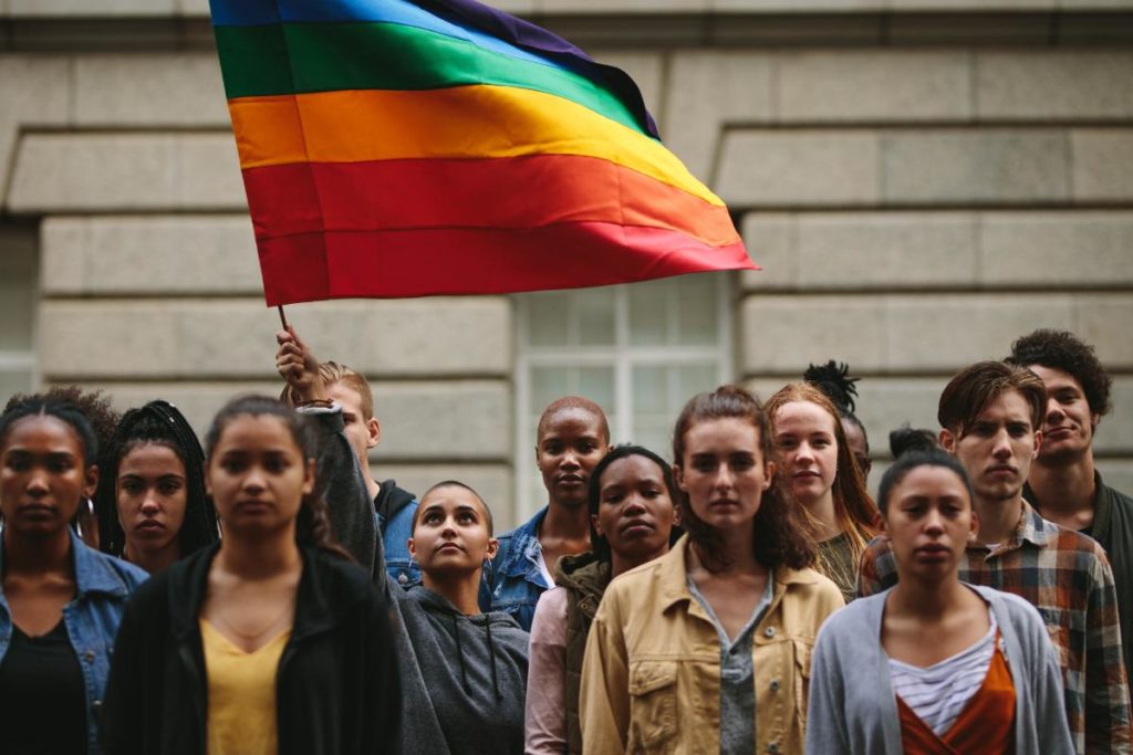 a group of people standing with a pride flag thinking about the history of the lgbtq community in the south