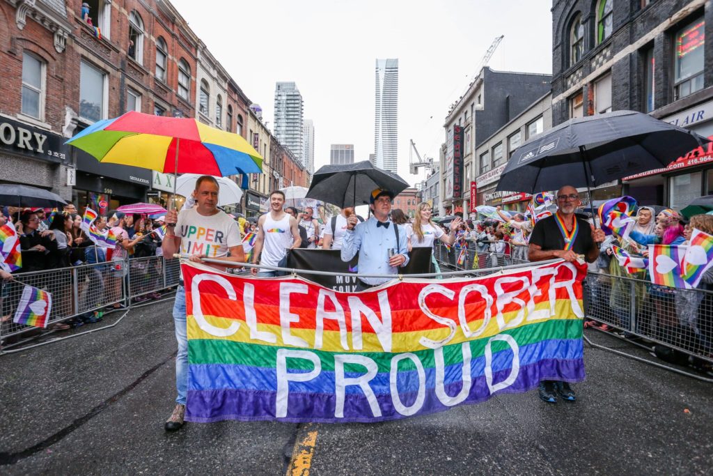LGBTQ New Year's Resolution. Marchers at a Pride Parade Holding a ‘Clean Sober And Proud’ Banner