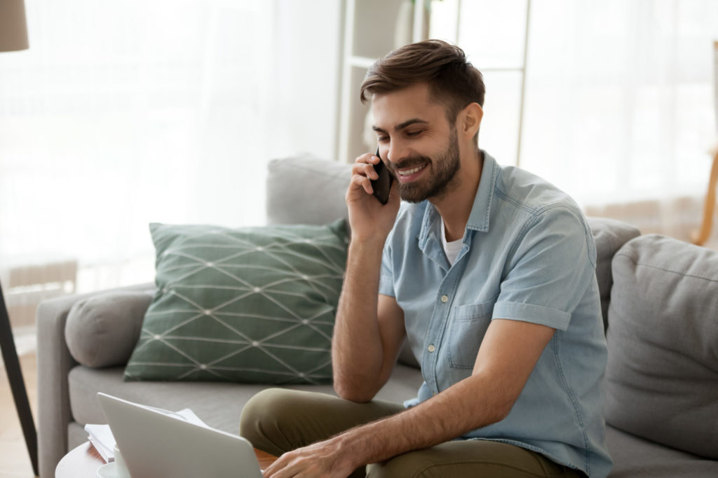 A man sitting on a couch talking on the phone.