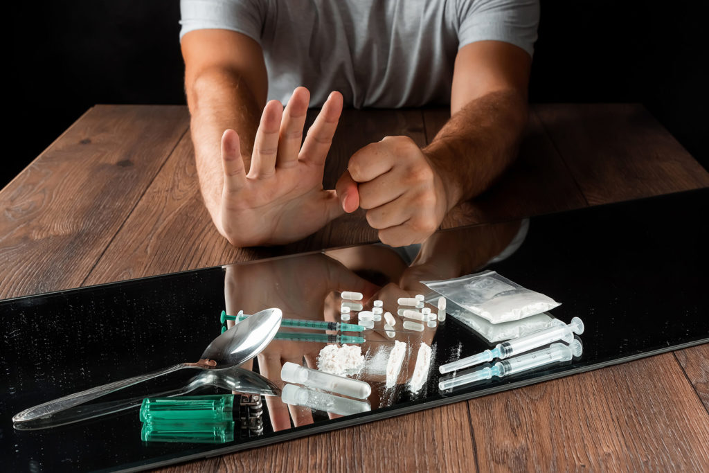 A close up of male hands pushing away drugs.