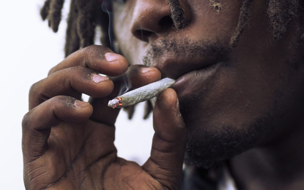 A close up of an African American man smoking a joint. 