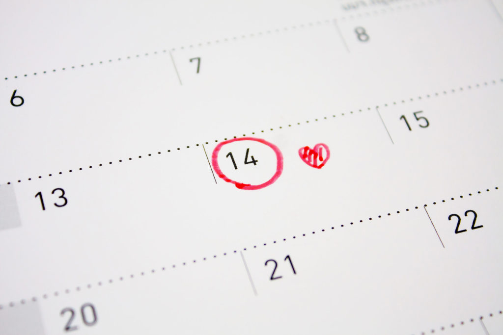 A calendar with a red circle around '14' and a heart.  