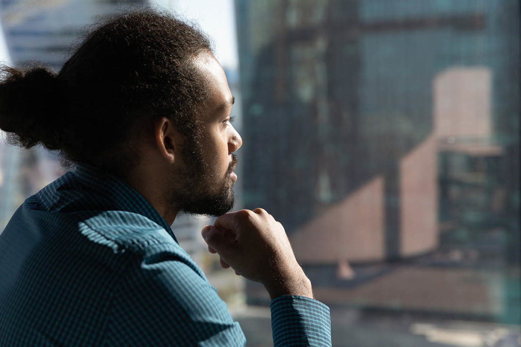 a man stares out the window as he considers an lgbtq inclusive alcohol detox center in southern california