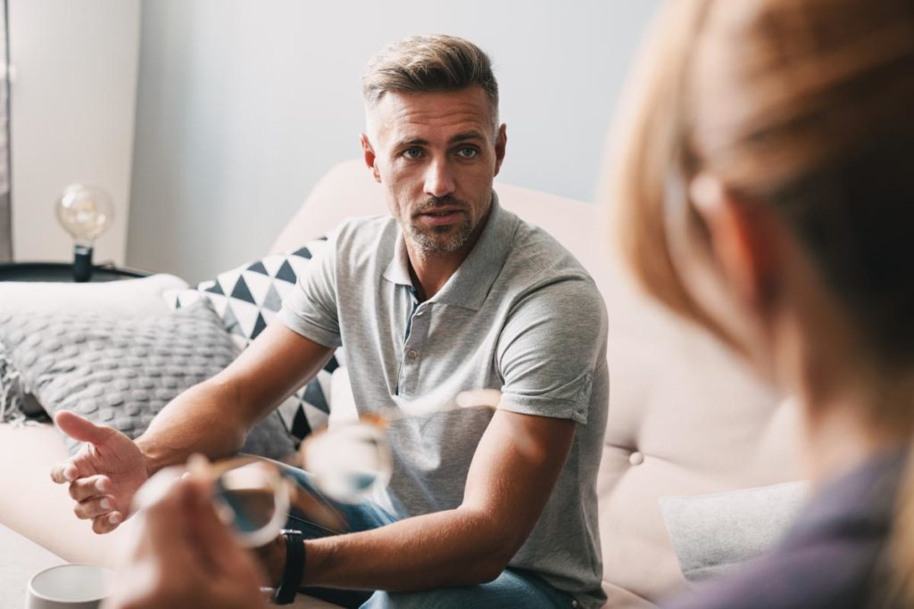 a person sits on a couch talking to a counselor about an lgbtq-inclusive iop