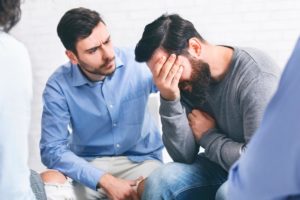 a person sits on a chair consoling another possibly in an lgbtq intensive outpatient program