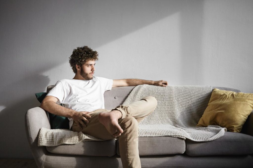 man sitting alone on couch wondering how to come down from a high