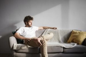 man sitting alone on couch wondering how to come down from a high