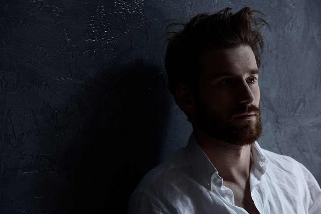 concerned man leaning against wall in a dark room learning what does fentanyl feel like