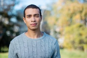 young man standing outside on a sunny day seriously contemplating an intensive outpatient program for gay men