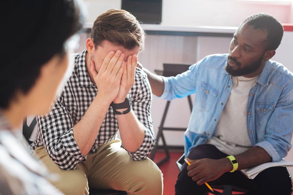 a group comforts a person in an lgbtq meth detox center