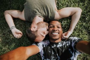 two people lie on the ground smiling in a php for gay men