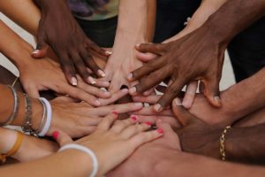 close up image of mens and womens hands from all ages and races clasped together to showcase gender differences in addiction and recovery