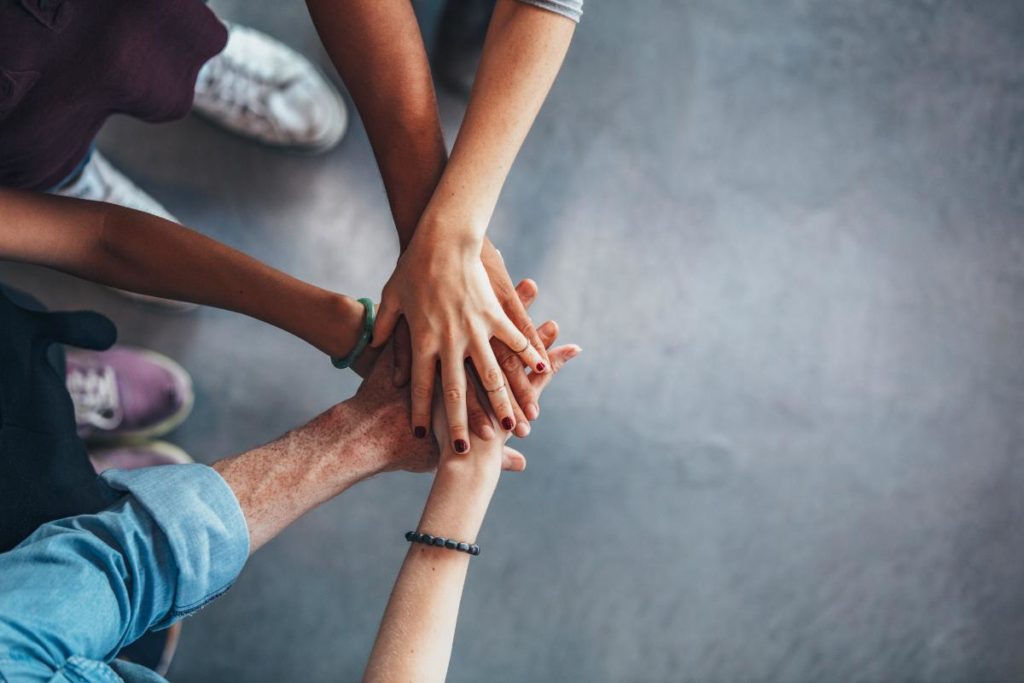 image of five people joining hands in an lgbtq inclusive residential treatment program