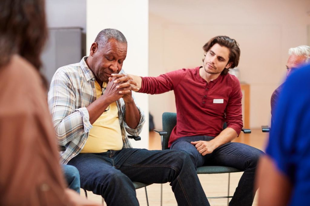 young man consoles older man while learning about a residential vs partial hospitalization program