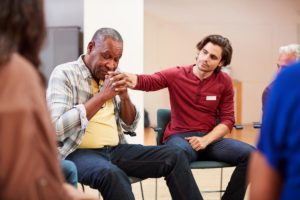 young man consoles older man while learning about a residential vs partial hospitalization program