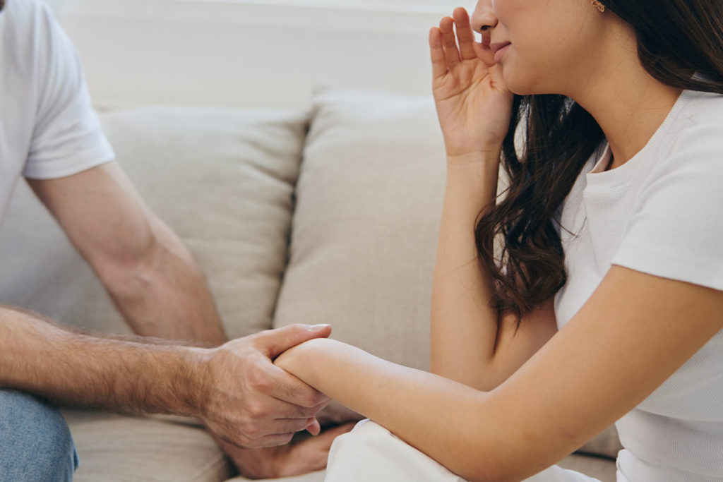 Man holding woman's hand, consoling her about drug addiction