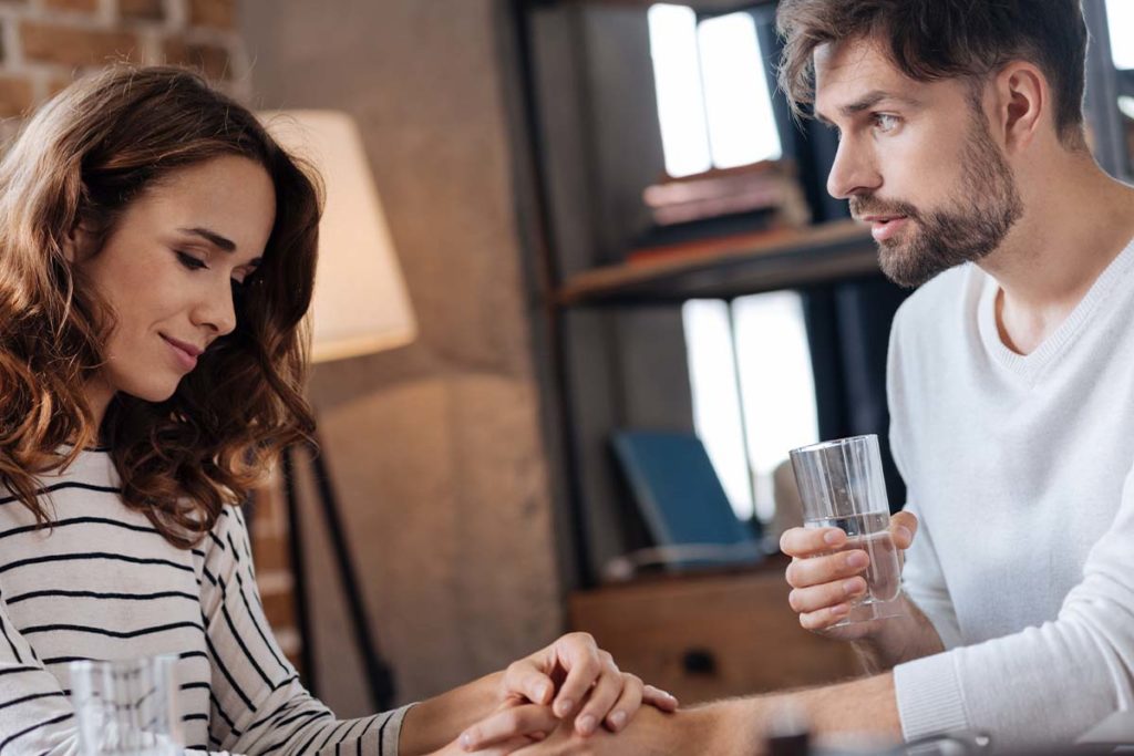 Woman holding hand of man with heroin addiction, comforting him