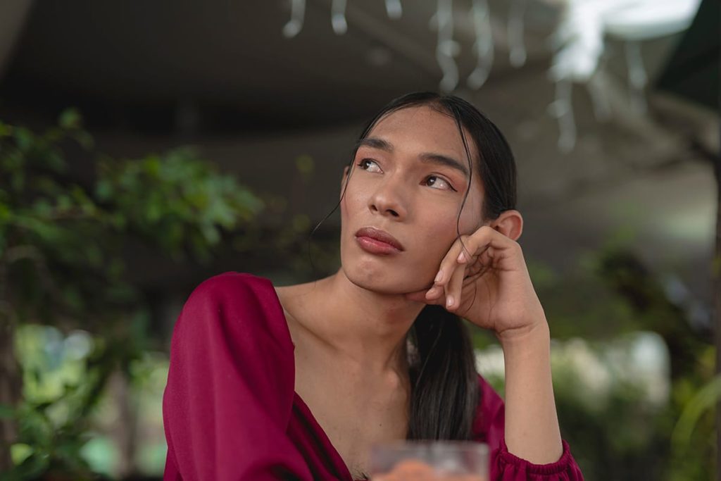 Transgender person ponders in red shirt about substance abuse