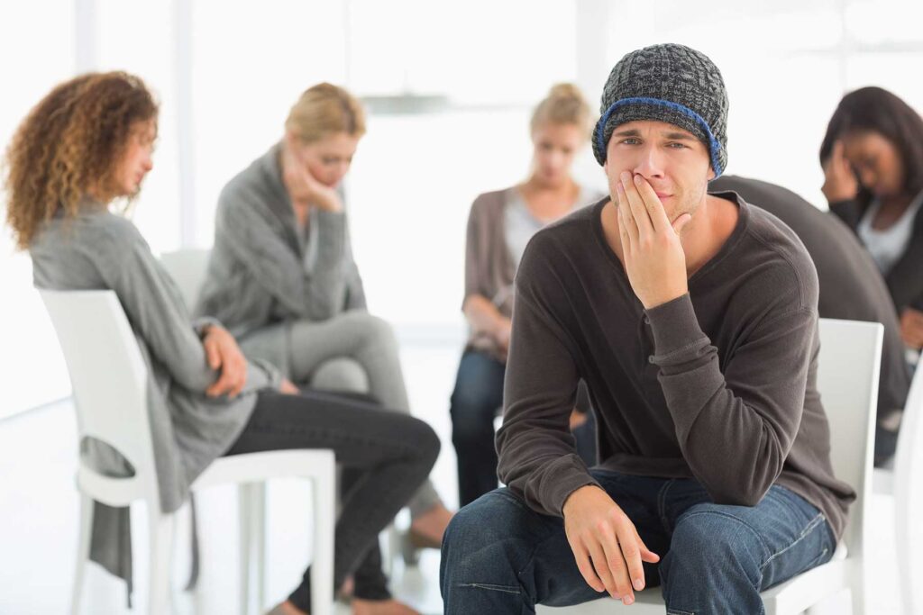 Person sitting in a waiting room, thinking about the benefits of ecstasy addiction rehab