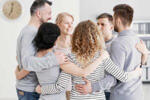 People standing in a cirlce and hugging each other at an ecstasy addiction rehab