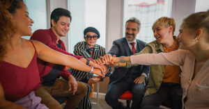 Several men and women seated in a circle and celebrating their progress in a group therapy program for behavioral health treatment