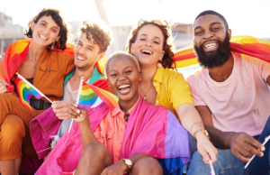 A group of LGBTQ community members are smiling and laughing because they know hot to stay safe during Pride