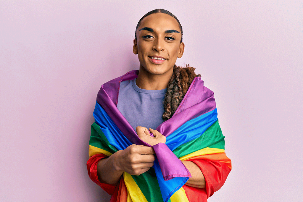 smiling LGBTQ youth wrapped in rainbow flag is staying mentally healthy during PRIDE