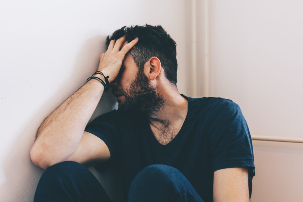 Man covering face in corner