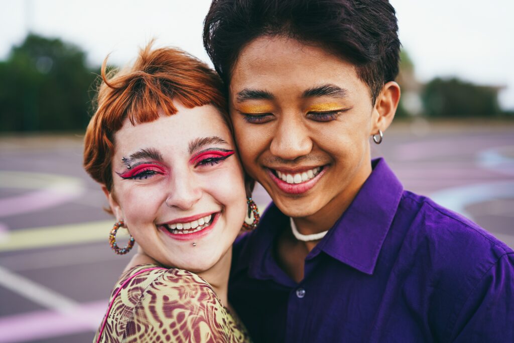 Two young friends with eye makeup hugging